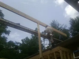 Carpenter setting a ridge beam over a new addition frame — Ice Dam Removal by Roofing Brothers in Houma