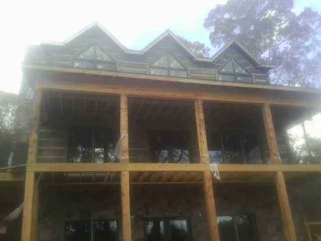 Dormers and porch framing on a large log home under construction — Roof Coating work by our crew in Houma